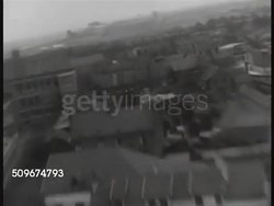 1942: AIRCRAFT IN FLIGHT: AERIAL Low altitude flight over rural land, over city & industrial area outside city.  (dark contrast). Instructional Video