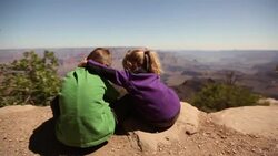 Young girl wraps her arm around young boy while overlooking the Grand Canyon Stock Footage
