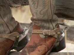 TU Cowboy's boots and spurs resting on a fence rail / Shell, Wyoming, United States Stock Footage