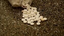 Bottle of Pills spilled all over the Counter white capsules with some random drugs mixed in higher angle Stock Footage