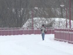 MS ZO Man drinking coffee and walking down snowy path with book in hand / Minneapolis, Minnesota, United States Stock Footage