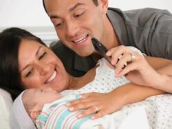 MS TU Mother and Father with Newborn Laying in Hospital Bed, Video Chatting on Cell Phone / Richmond, Virginia, USA Stock Footage