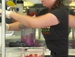 MS TU juice bar worker pours almond milk into plastic blender jar to prepare smoothie mix with spatula Stock Footage
