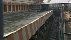 Commuters cross a sky bridge over a crowded platform at a railway station in India. Stock Footage