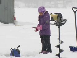 WS Girl reeling in line ice fishing during winter / Minneapolis, Minnesota, USA Stock Footage