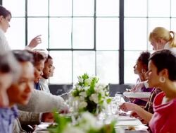 MS waitresses bringing food and wine to table of friends sitting at banquet table  Stock Footage