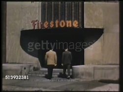 1950: FIRESTONE PLASTIC: COLOR: VS Firestone manufacturing building, men entering. INT VS Workers wrapping red sheets of plastic from plastic producing machine. Synthetic rubber, GRS, GR-S, plant, industrial Instructional Video