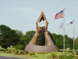 Dolly past world's largest praying hands bronze statue at Oral Robert's University Stock Footage