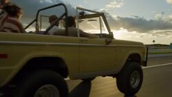 Friends cruising in classic Ford Bronco hold up American flag in the wind Stock Footage