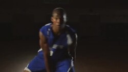 A male basketball player approaches the spotlight and dribbles a basketball on a gym court. Stock Footage