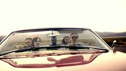 Friends driving through desert in red convertible throw hands in the air and clap Stock Footage