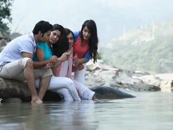 Group of friends watching a mobile phone at riverbank  Stock Footage