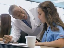 Young Hispanic nursing student being tutored by senior professor of medicine Stock Footage