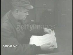 1951: KOREAN WAR: P.O.W. LIST: MS Newspaper headlines, 'Reds Bow to UN...' VS United Nations officers in room checking prisoner of war lists, checking names on lists. POW Instructional Video