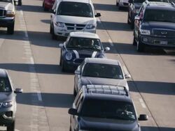 Long lens, overhead, huge traffic congestion passes under bridge on hot interstate highway. Stock Footage