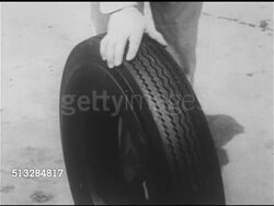 1952: SPONSOR BREAK: MS Male service station attendant in Gulf uniform rolling tire off display rack, TD MS Tire being held by male hand. CU Gulf tire tread, male finger pointing out even, wide width, tire turning w/ GULF in center.   Early commercials. Instructional Video