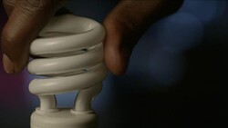 Close up CFL spiral lightbulb is twisted into a socket, a switch is turned on, it becomes illuminated. Stock Footage