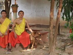 WS SLO MO Two buddhist monks sitting in yard with dog / Vientiane, Laos Stock Footage