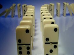 High Speed Dominoes - MS 2 symmetrical rows of dominoes stretch away from camera and curve around in opposite directions, 2 rows fall over Stock Footage