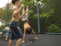 WS SLO MO shot of three Caucasian male children on trampoline with arms around each other, bouncing and falling / Stanford, Connecticut, United States  Stock Footage