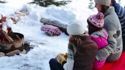 Family sitting near fire pit on snowy patio Stock Footage