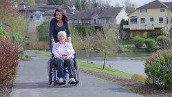 Elderly woman in wheelchair enjoying the outdoors with her caregiver Stock Footage