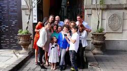 MS TU SWISH PAN Young boy showing photo on smartphone to smiling multigenerational family in front of restaurant entrance Stock Footage