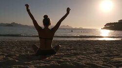 Brazilian girl stretches with arms overhead, lowers and twists on Copacabana Beach Stock Footage