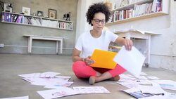 Designer with laptop surrounded by proofs on office floor Stock Footage