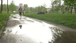 Young girl jumping in puddles with umbrella Stock Footage