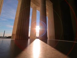 A tracking shot with a lens flare of the bottom of the pillars of the Lincoln Memorial. Stock Footage