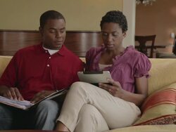 MS PAN Couple enter living room with papers and tablet computer sitting down on sofa / Portland, Oregon, United States  Stock Footage