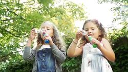 Girls blowing bubbles in backyard Stock Footage
