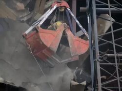 Warehouse buidling demolition 1. Close-up.  Orange clamshell bucket crane chewing at tar paper and lots of dust and debris flying away. Stock Footage