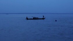 View from a speedboat at twilight crossing a wide expanse of open water in the Bangladesh delta specifically the River Camuna with small boats net fishing Stock Footage
