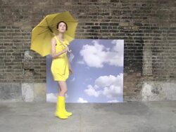 Young woman in yellow enters scene with umbrella, checks for rain and walks off Stock Footage