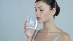 Portrait of young woman drinking a glass of water looking away from camera Stock Footage