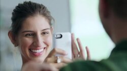 Laughing girl takes smartphone photo of boy posing with sweater in trendy clothing shop Stock Footage