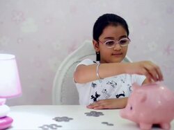 MS Girl putting coins in piggy bank / India Stock Footage