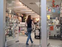 WS TS customer enters record store in mall selling records and t-shirts and novelty items with store manager on elevated cash register platform / Palm Desert, California, USA Stock Footage