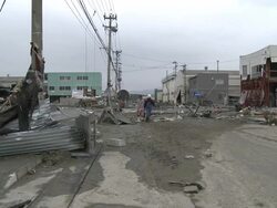 Destruction caused by tsunami after magnitude 9 Tohoku earthquake, north east Japan, March 2011. Men walk through wrecked streets of Ishinomaki City port, Miyagi Prefecture Stock Footage
