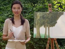 MS woman holding a paintbrush standing in front of a painting. Stock Footage