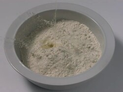 High speed Egg yolk falls into bowl of flour, top shot Stock Footage