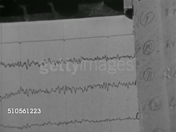 1965: NEUROSCIENCE: MACHINES: TD MS Electroencephalogram (EEG) printing brain wave record on paper, MS Two scientists talking while watching, three scientists standing at machine, male adjusting knob FG. Instructional Video