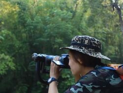 Wildlife Photographer taking picture of bird in the rainforest jungle Stock Footage
