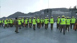 A platoon of soldiers in reflective vests marches forward, then turns as an officer watches. Stock Footage