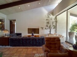 TS across living room with 1971 original furniture in mid-century Cody designed home with clay floor tiles, floor-to-ceiling glass windows and cathedral ceiling Stock Footage