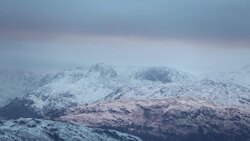 Reflected light from a hole in the cloud at sunset, creating a warm glow looking towards the Langdale Pikes from Wansfell in the Lake District, UK Stock Footage