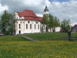WS Famous baroque church inmidth spring meadow with some trees and houses / Wieskirche, Steingaden, Bavaria, Germany Stock Footage