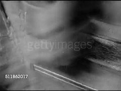 1942: DURHAM, NORTH CAROLINA: LIGGET-MEYERS TOBACCO COMPANY: CU Fast blades cutting tobacco. LS Tobacco being turned out of machines onto conveyor belt. MS Conveyors belts dumping tobacco in pile. Male worker loading cut leaf into machine for blending Instructional Video